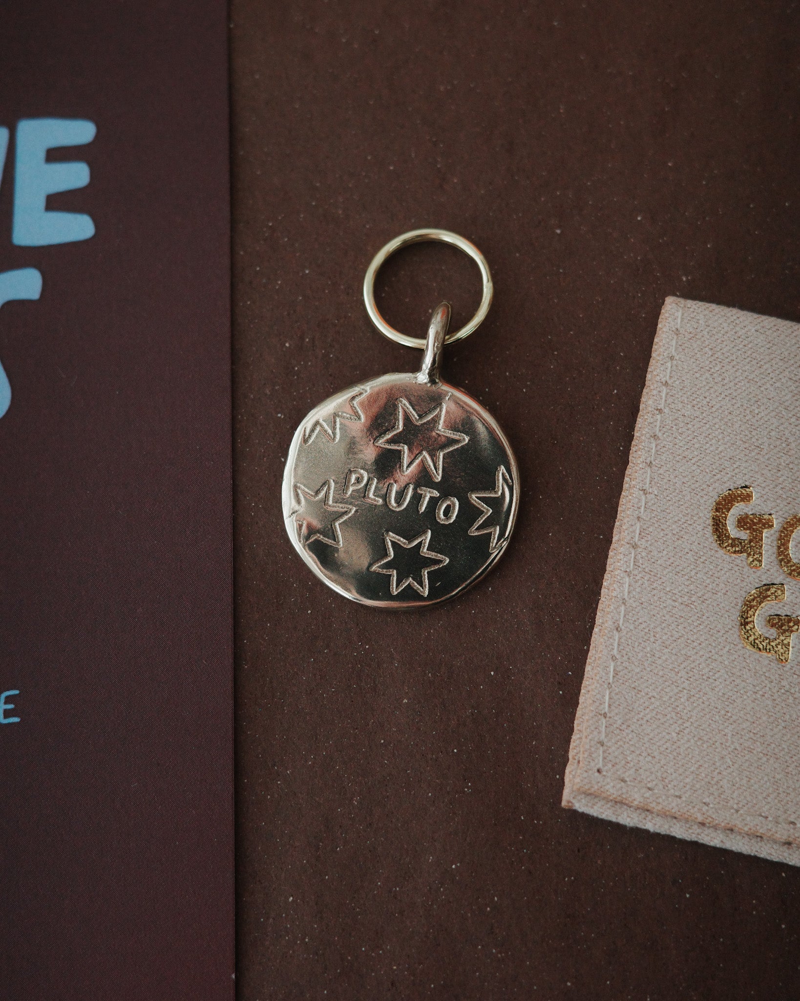 Got the goods pet supplies. Unique cool fun pet tags and ideas. Custom round coin circle pet tag in brass. Hand carved with dogs name and stars doodles unique and playful bespoke pet tags for dogs and cats.